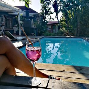 a woman with a glass of wine next to a swimming pool at Aloha Lodge in Cape Town