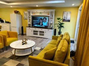 Home away from home في وينيبيغ: غرفة معيشة مع أريكة صفراء وتلفزيون