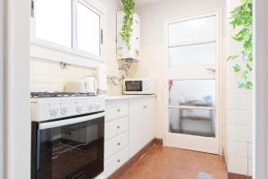 cocina blanca con fogones y ventana en Fliphaus Borges 2200 - Petit Apt Palermo Soho en Buenos Aires