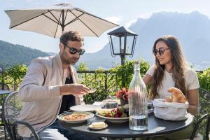 Ein Mann und eine Frau sitzen am Tisch und essen Essen. in der Unterkunft Aparthotel Ansitz Felsenheim in Lermoos