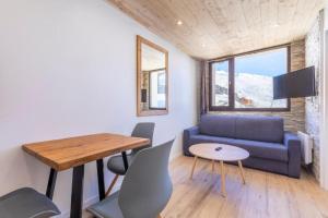 een woonkamer met een blauwe bank en een tafel bij Résidence Le Médian - Les Ménuires in Les Menuires