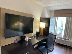 een hotelkamer met een bureau en een groot televisiescherm bij Sleep Inn & Suites Columbus State University Area in Columbus