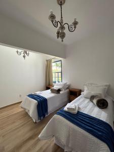 1 dormitorio con 2 camas y lámpara de araña en Casa da Tuta Pousada en Tiradentes