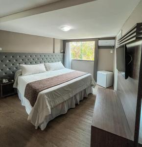 a bedroom with a large bed and a television at Hotel Village Confort Campina Grande in Campina Grande