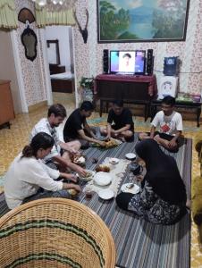 un grupo de personas sentadas alrededor de una mesa comiendo comida en Mando Homestay II, en Bukittinggi