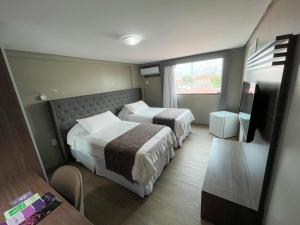 a hotel room with two beds and a table at Hotel Village Confort Campina Grande in Campina Grande