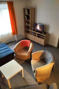 un soggiorno con diverse sedie e TV di Apartmán Banská Bystrica Fortnička a Banská Bystrica