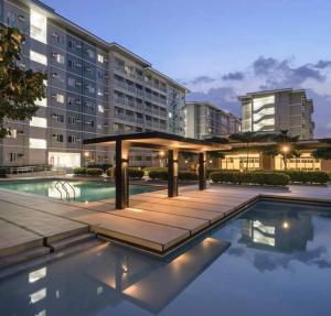 a swimming pool with a gazebo in front of a building at Chelsea Suite's Esthetic Staycation at Trees Residence QC in Manila