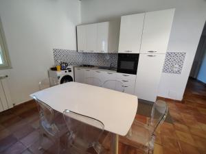 a kitchen with white cabinets and a white table and chairs at Casa Titì in Cefalù