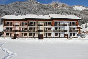 a building in the snow in front of a mountain at Appartamento Contolini in Mazzin