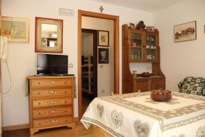 a bedroom with a tv and a dresser with a table at Appartamento Contolini in Mazzin