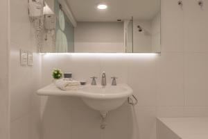 Baño blanco con lavabo y espejo en Fliphaus Oro 2200 - Lux Duplex Palermo Soho en Buenos Aires
