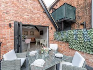 a patio with a table and chairs and a brick wall at Pass the Keys Dahlia Contemporary town centre apartment in Shrewsbury