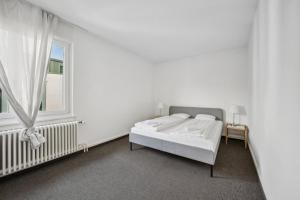 a white bedroom with a bed and a window at Dohlenweg 2 in Zürich