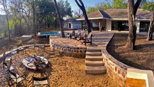 une arrière-cour avec des chaises, un foyer extérieur et une maison dans l'établissement Mbuluzi Game Reserve, à Simunye