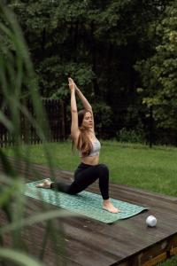 una mujer haciendo una pose de yoga en una alfombra en Domki Momenty en Słajszewo