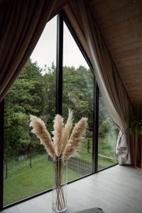 a vase filled with feathers on a table in front of a window at Domki Momenty in Słajszewo