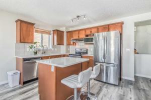 a kitchen with wooden cabinets and a stainless steel refrigerator at Calgary Mountain Gorgeous Single House Close Airport & Free Parking in Calgary