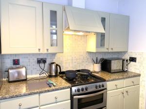 a kitchen with white cabinets and a stove top oven at Stylish 3-bedroom home in Canterbury City-Centre - Superb Location! in Canterbury +18 photos