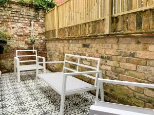 two white chairs sitting next to a brick wall at Stylish 3-bedroom home in Canterbury City-Centre - Superb Location! in Canterbury