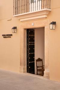una puerta a un edificio con una silla y botellas de vino en Casa Pizarro Hotel, en Cáceres