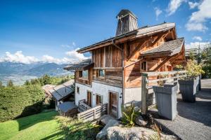 a wooden house on a hill with mountains in the background at Chalet Purdey Combloux - BY EMERALD STAY in Combloux