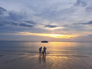 three people standing on the beach at sunset at Baan Long Beach in Ko Lanta