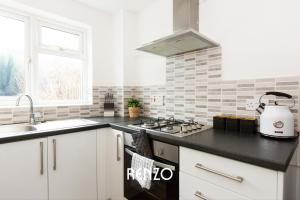 a kitchen with white cabinets and a black counter top at Charming 3-bed Home in Nottingham by Renzo, Driveway, Smart TV with Netflix! in Nottingham