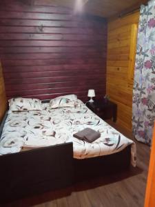 1 cama en un dormitorio con pared de madera en Refugio do Lentinho, en Entre Ambos os Rios