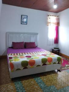 um quarto com uma cama com um edredão colorido em Mando Homestay II em Bukittinggi