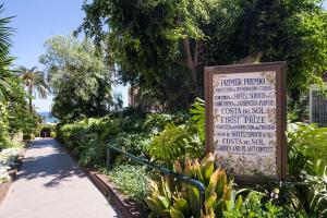 um sinal em frente a um jardim com um passeio em Hotel Best Siroco em Benalmádena