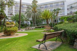 einem Park mit zwei Bänken und einem Gebäude in der Unterkunft Hotel Best Siroco in Benalmádena