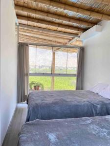 1 dormitorio con 2 camas y ventana grande en Mirador del Paraiso, en Lunahuaná