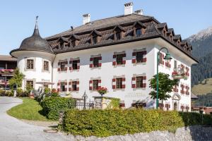 a large white building with a black roof at Aparthotel Ansitz Felsenheim in Lermoos