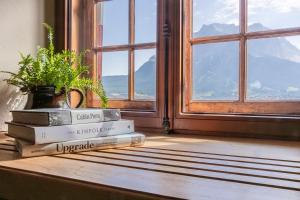 a stack of books sitting on a table next to a window at Aparthotel Ansitz Felsenheim in Lermoos +237 photos
