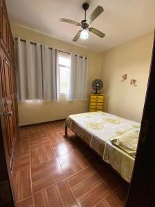 Casa acolhedora e familiar في كامبوس دوس جويتاكازيس: غرفة نوم بسرير ومروحة سقف