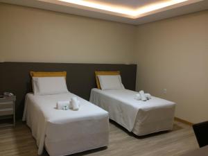 a room with two beds with white sheets at Nhtel Acomodações in Novo Hamburgo