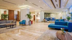 a lobby with blue couches and chairs and tables at SeaVille Beach Hotel by Elite Hotels & Resorts in Ain Sokhna