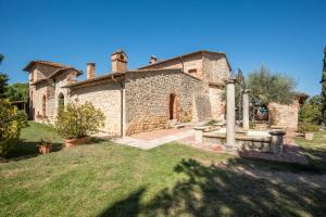 una antigua casa de piedra con un patio de césped en Appartamento il Granaio en Rapolano Terme