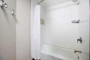 a bathroom with a shower and a white shower curtain at The Worthington Renaissance Fort Worth Hotel in Fort Worth