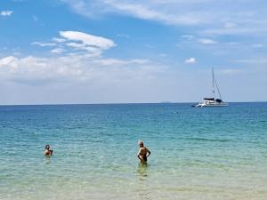 two people in the ocean with a boat in the water at Baan Long Beach in Ko Lanta