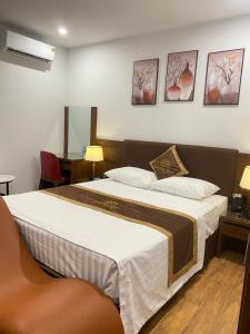 ハノイにあるLuxTel Hotel Tây Hồのベッドルーム1室(大型ベッド1台付)が備わります。壁に3枚の写真が飾られています。