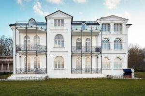 une grande maison blanche avec une pelouse devant elle dans l'établissement Villa Greif Wohnung 05, à Heiligendamm
