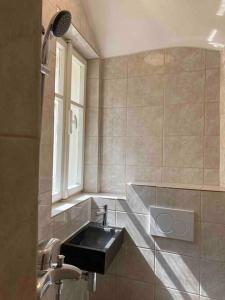 a bathroom with a black sink and a window at Studio in gothic house, 50m to the Old Town Square in Prague