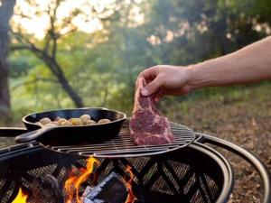 a person holding a piece of meat on a grill at Tentrr Signature Site - Happy Hollow Hideaway Creekside in Pigeon Forge