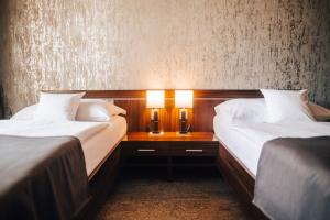 Hotel Elegance في شومبيرك: سريرين في غرفة الفندق وعليها مصباحين