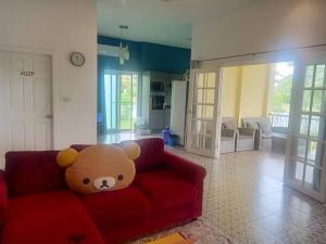 a teddy bear sitting on a red couch in a living room at บ้านพักในสวนK&N2 