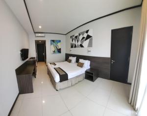 een slaapkamer met een bed en een televisie. bij Summer Hills Hotel & Villas Bandung in Bandung