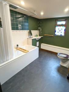 a bathroom with a bath tub and a toilet at 3-Bed, Sleeps 6, 1 Bath, Parking, WiFi in Shalford