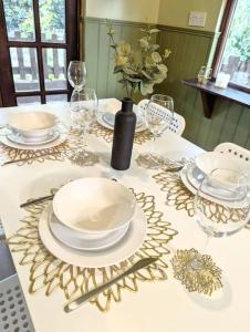 a table with plates and glasses and a vase with flowers at 3-Bed, Sleeps 6, 1 Bath, Parking, WiFi in Shalford